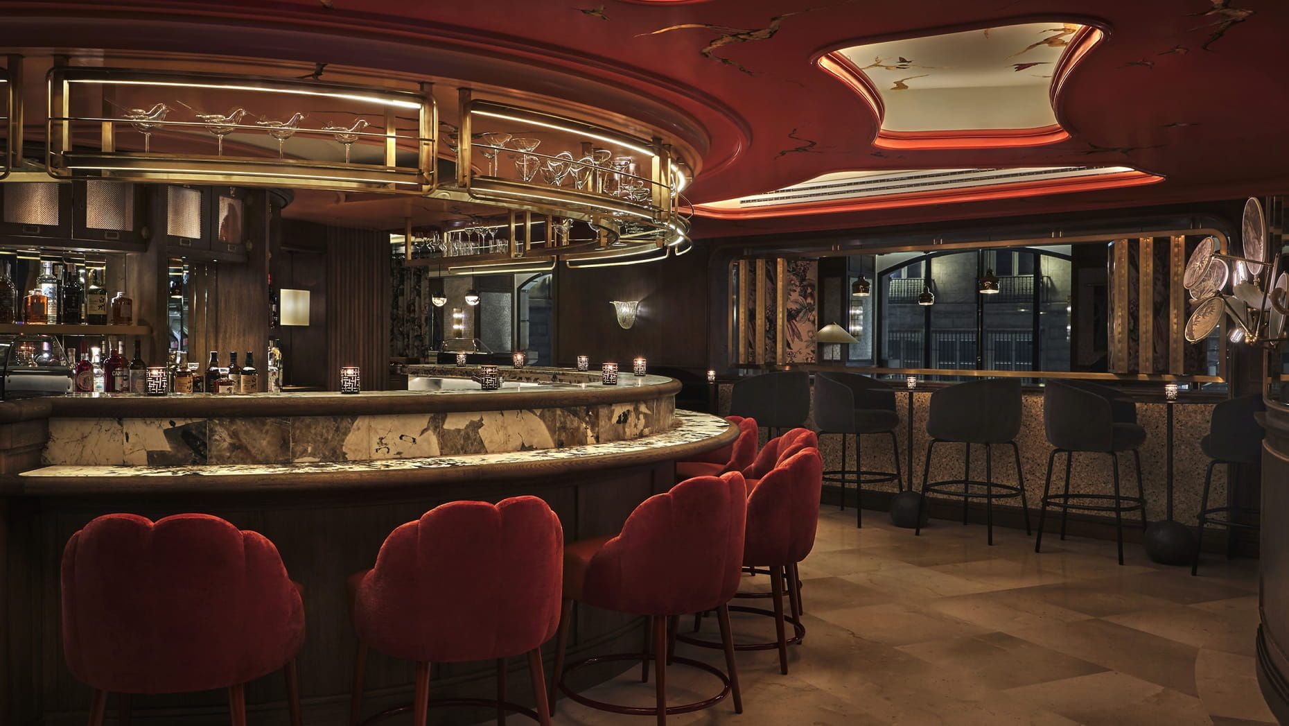 The curved marble bar at Isa, Four Seasons Madrid, with red velvet stools